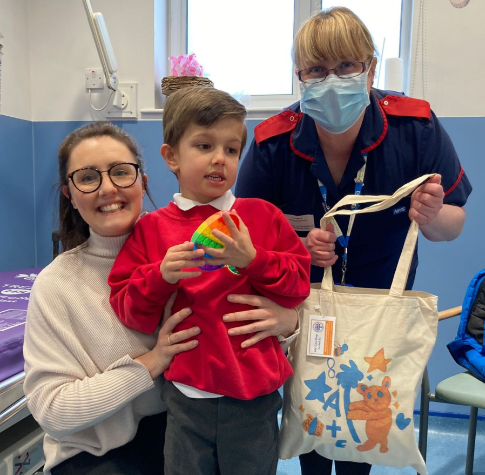 Colleague giving young patient and mum a A&E Care Bag. 